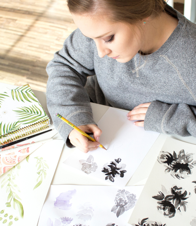 Woman drawing flowers at a desk.