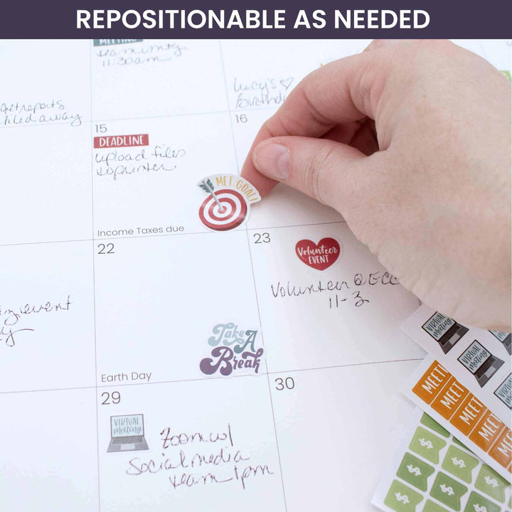 Hand placing a sticker on a calendar, showcasing Bloom Workday Essentials Planner Stickers.