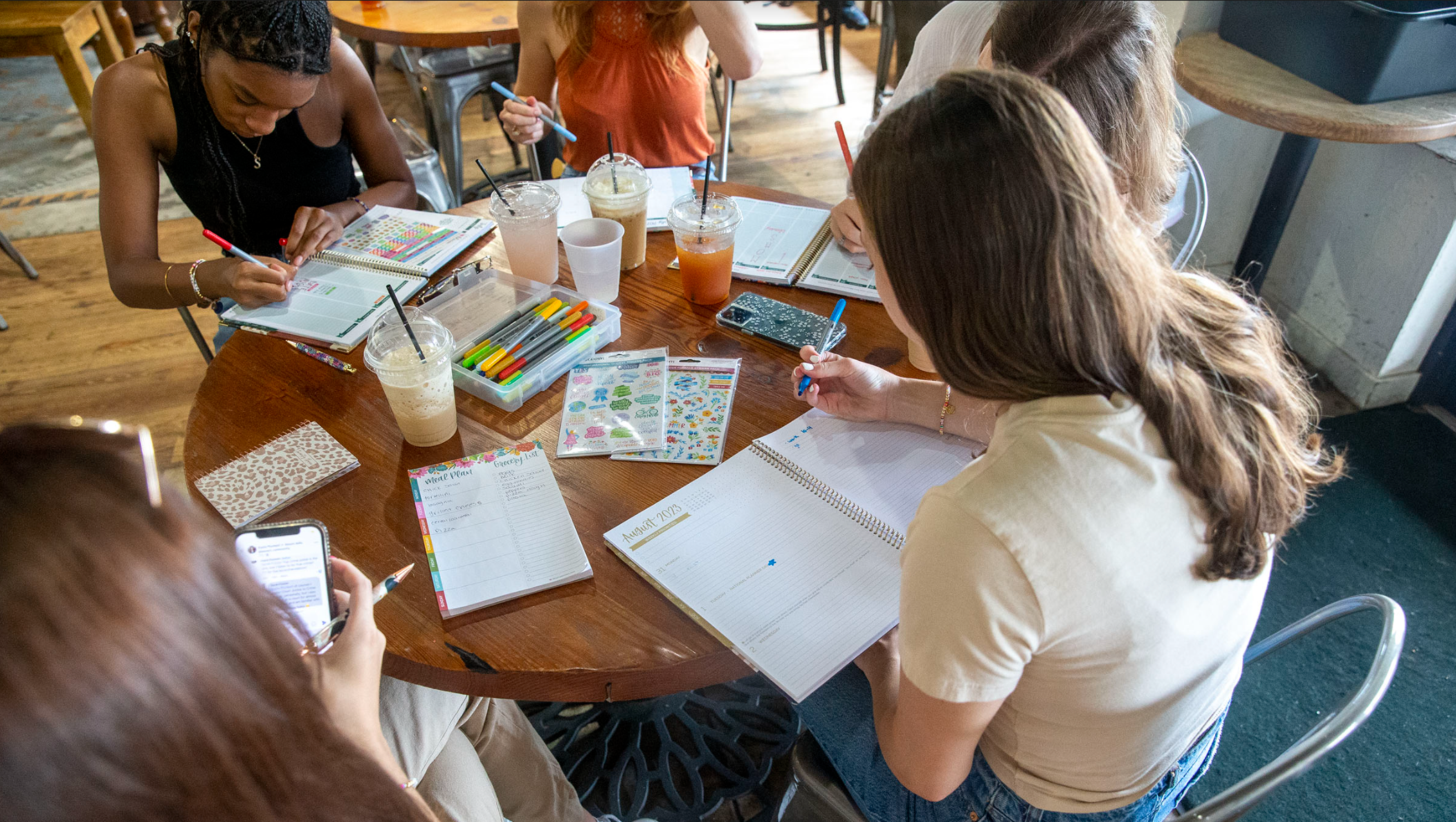 A group of women sitting at a coffee shop planning together