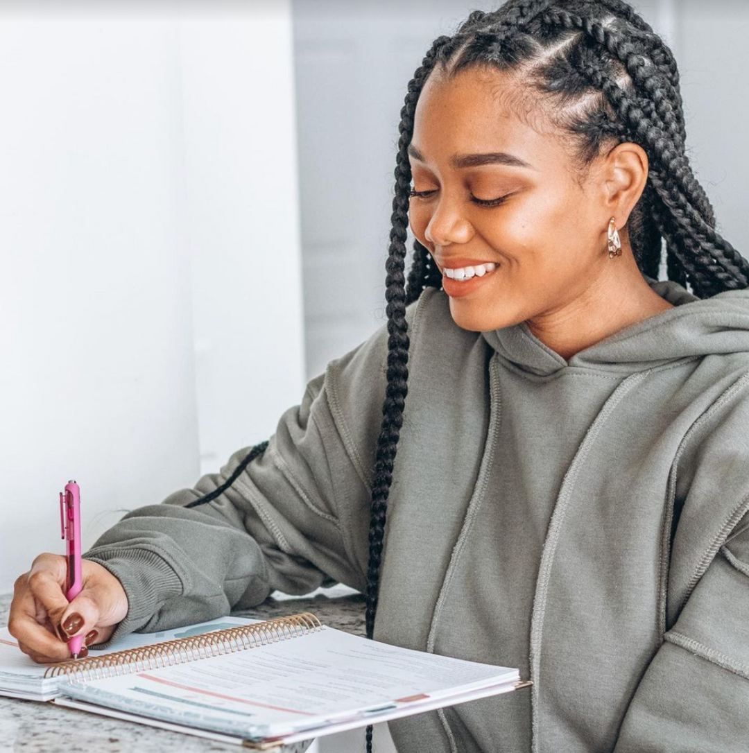 Woman at a desk writing in her planner.