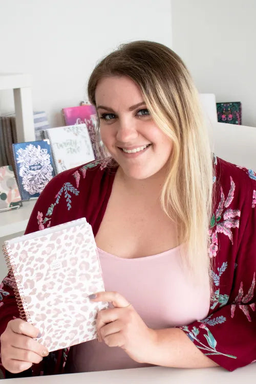 girl at desk holding leopard planner