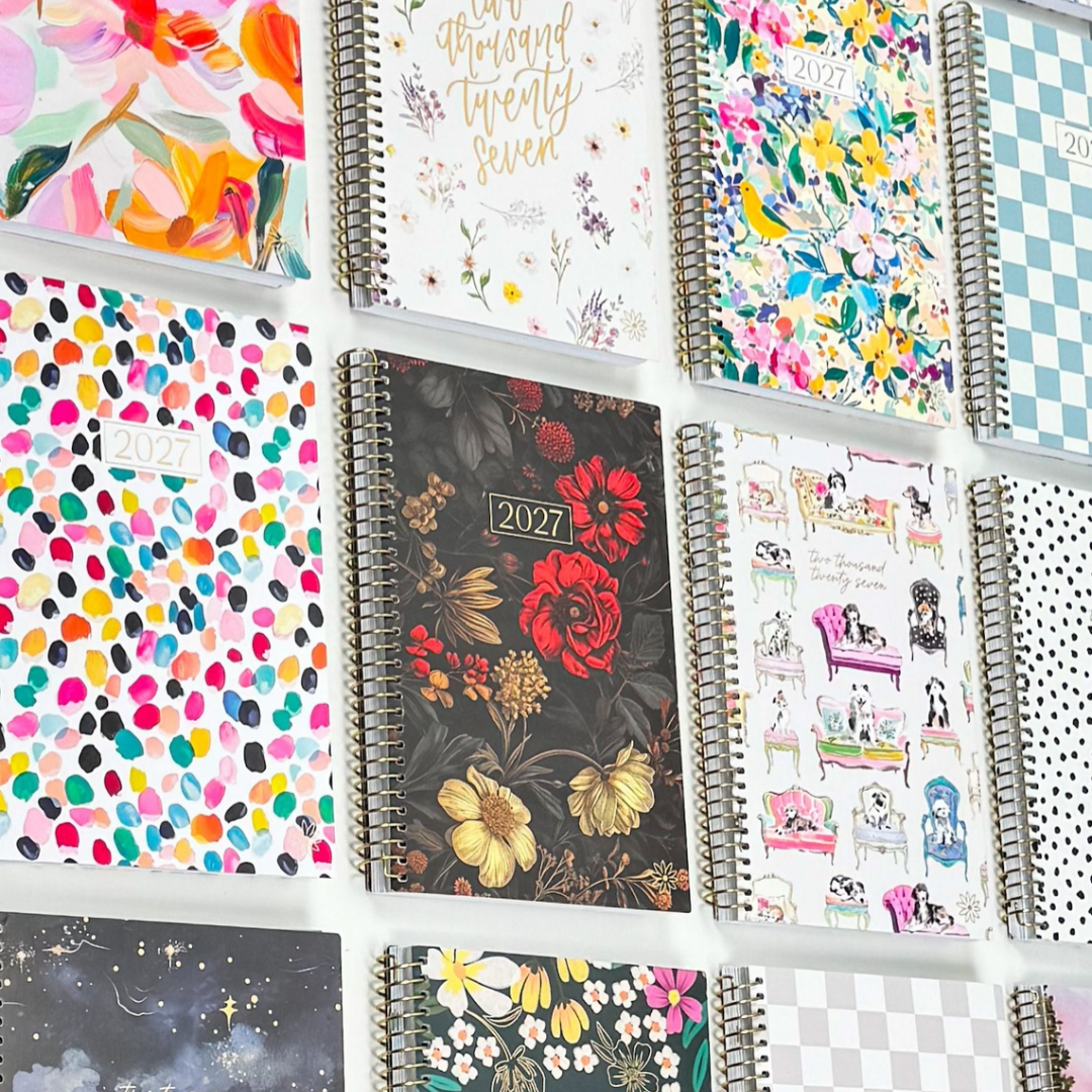 Various colorful 2027 soft cover planners from bloom daily planners arranged flat on a white surface 