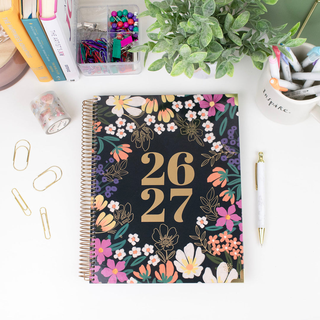 Floral notebook with years 2026 and 2027 on a desk with stationery items.