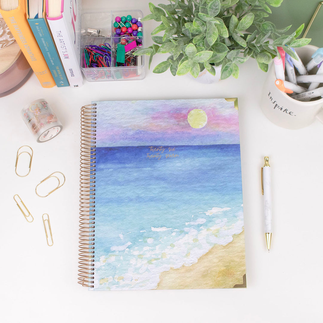 Planner with beach design on a desk with stationery items