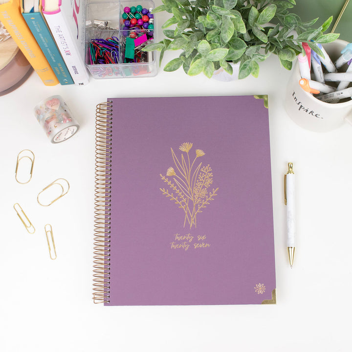 Purple notebook with floral design on a desk with stationery items