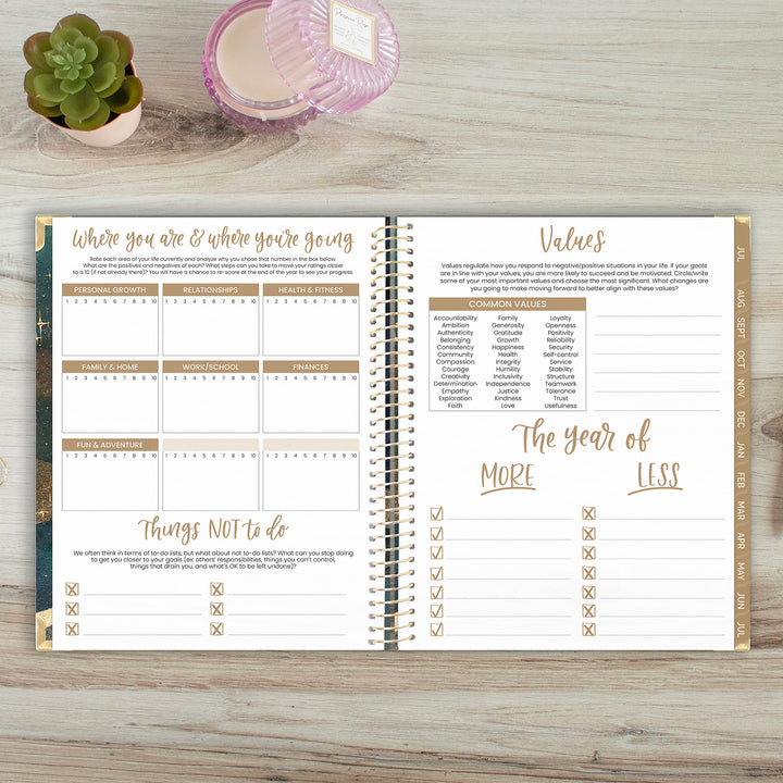 Open planner on a wooden surface with a plant and candle in the background