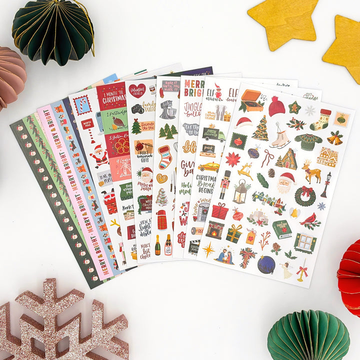 Set of Christmas sticker sheets fanned out with red, green, and gold holiday designs