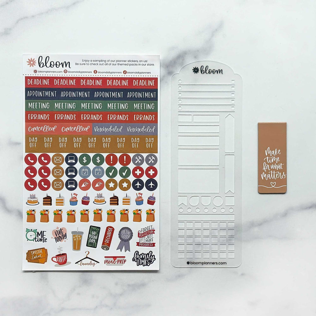 Bloom planner sticker kit displayed on a white marble background, featuring a sheet of colorful planner stickers, a white planner insert sheet, and a brown sticky note with white text.