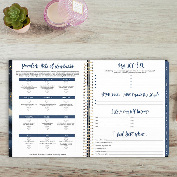Open planner on a wooden surface with a plant and candle in the background