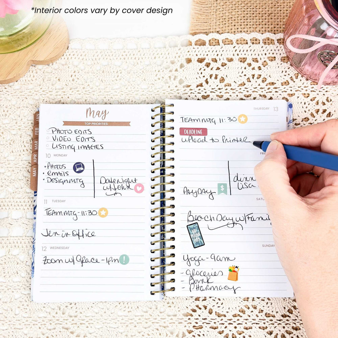 Person using a planner with a hand holding a pen on a textured surface