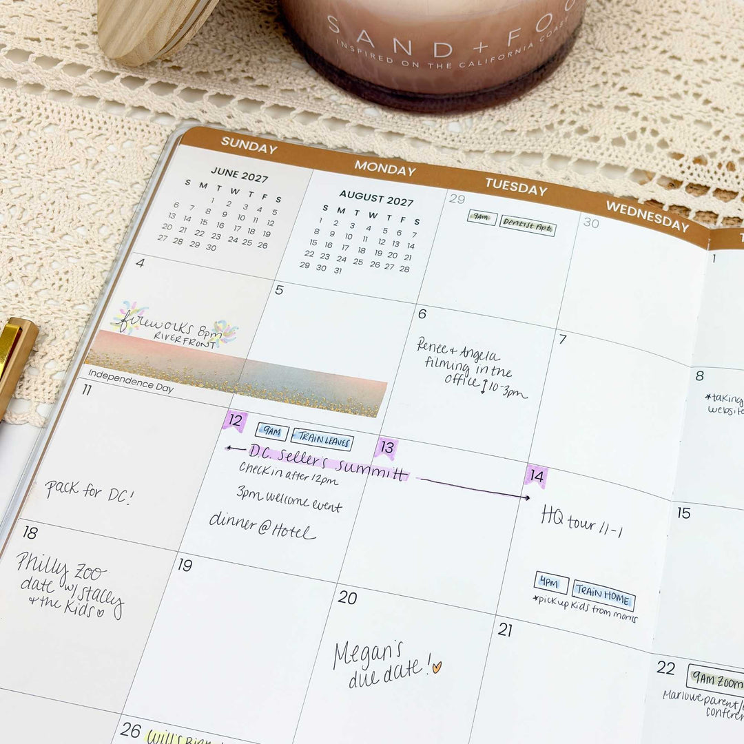 Calendar with handwritten notes on a textured surface with a candle and pen.