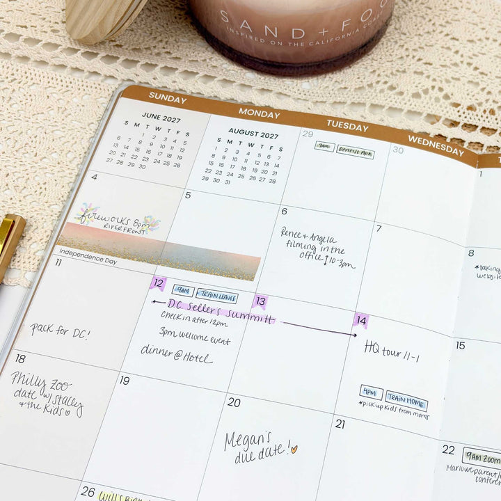 Calendar with handwritten notes on a textured surface with a candle and pen.