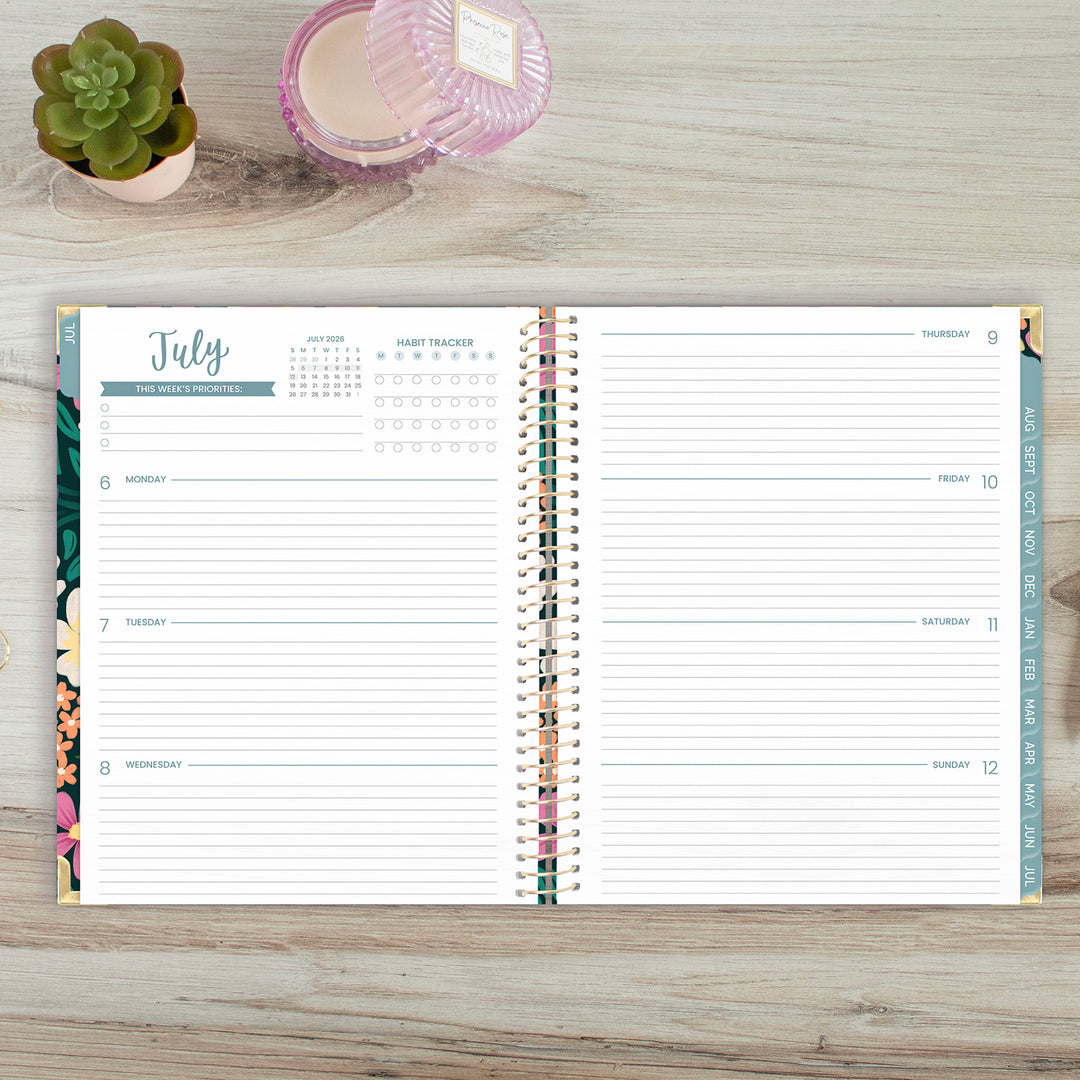 Open planner on a wooden surface with a plant and container in the background