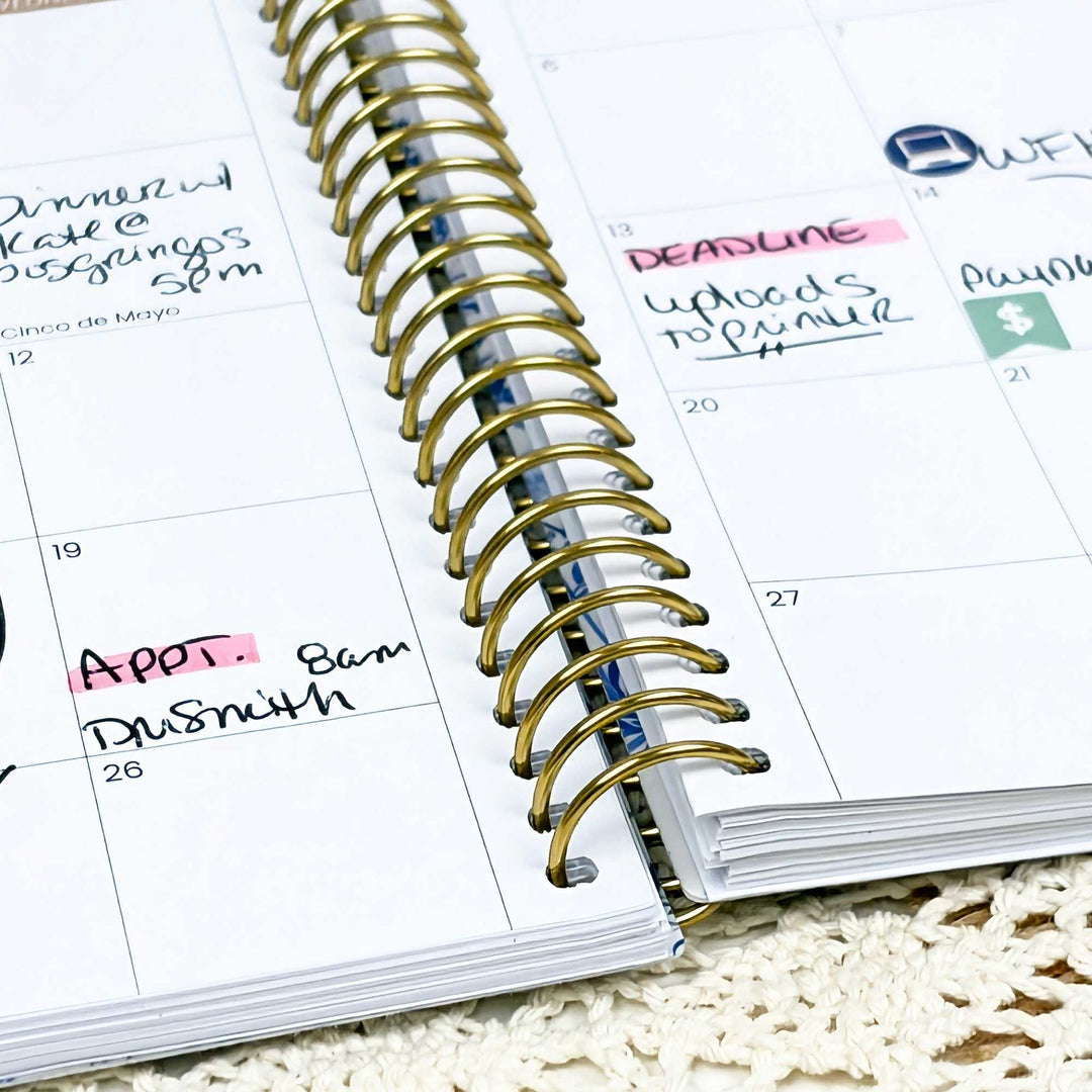 Open planner with gold spiral binding on a textured surface