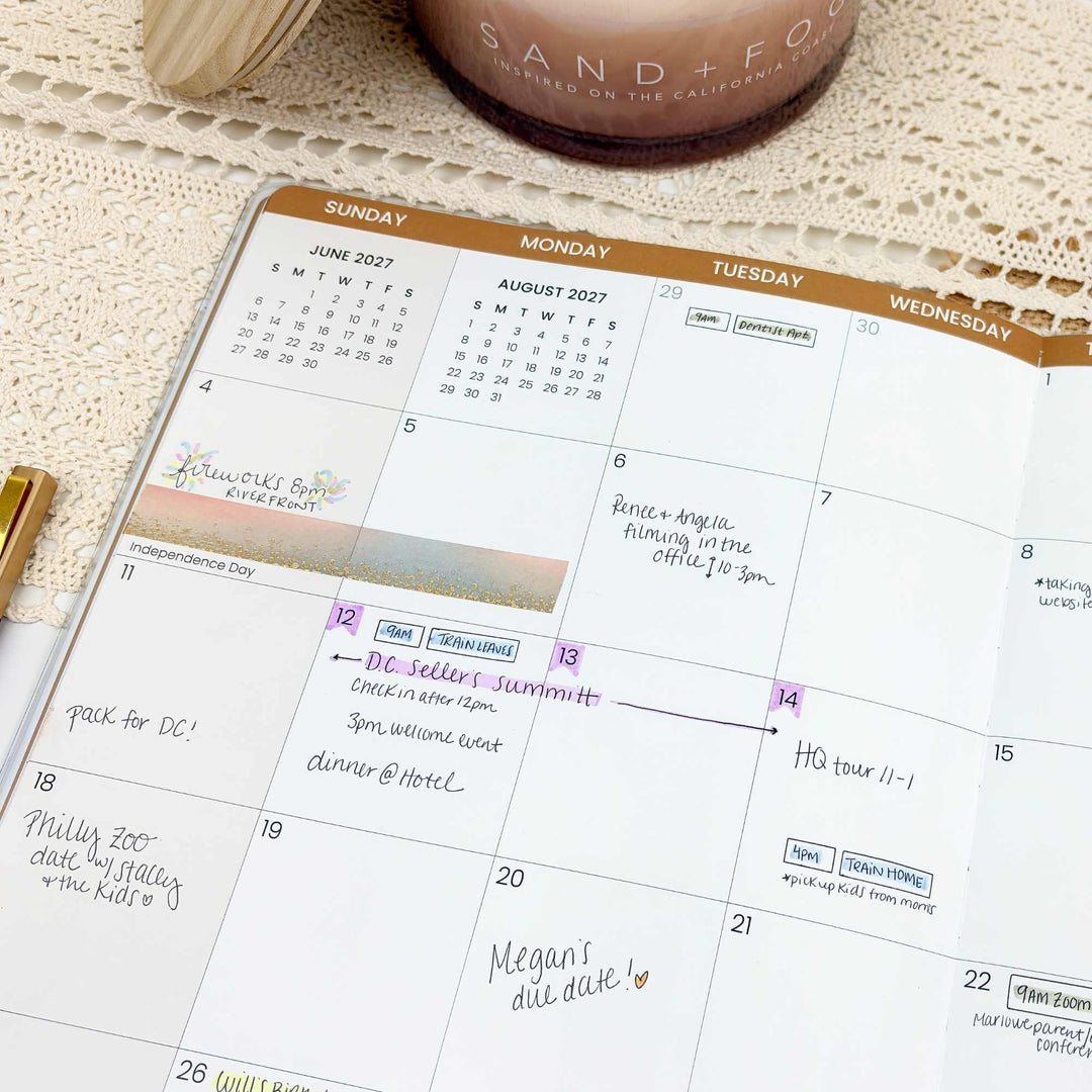 Calendar with handwritten notes on a textured surface with a candle and pen.