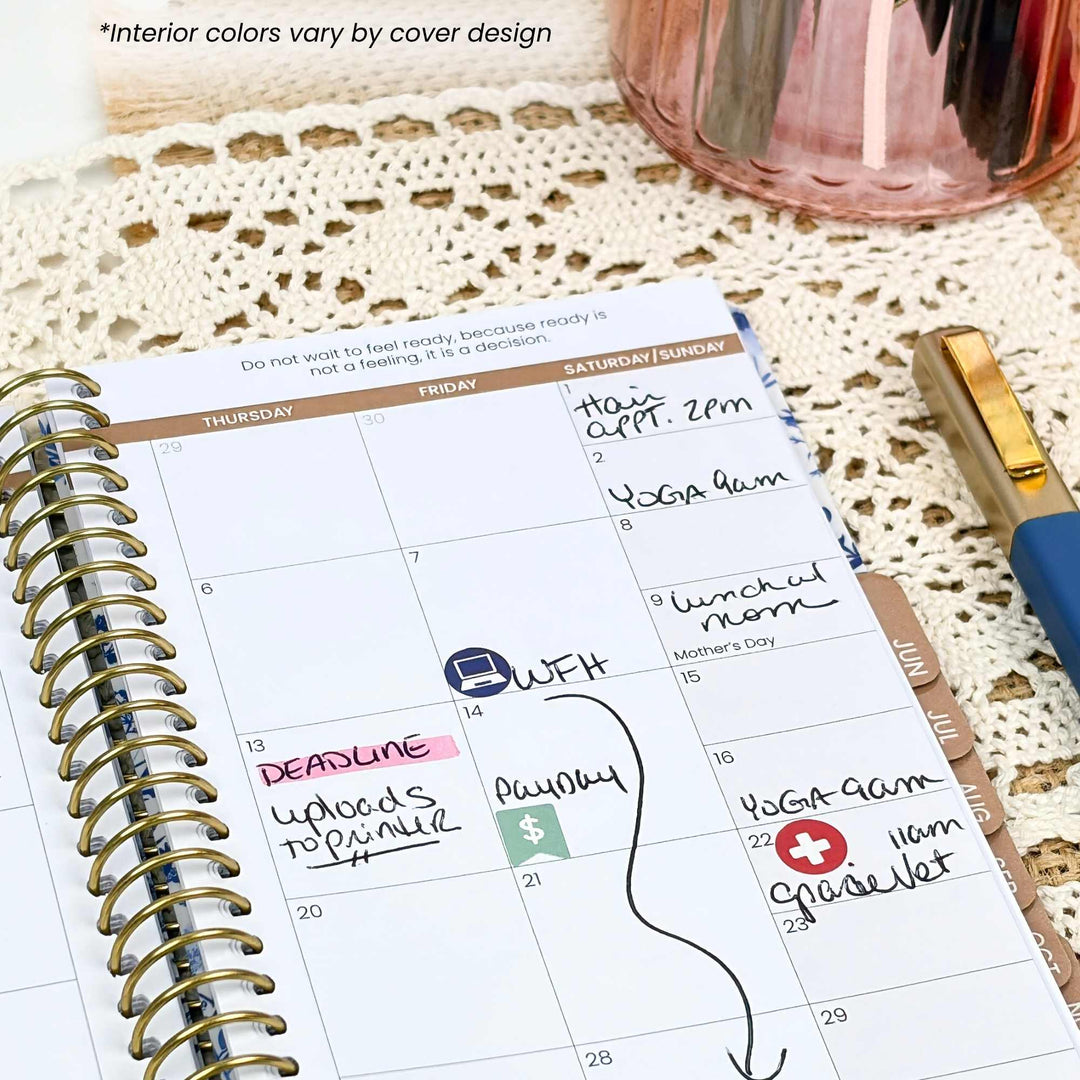 A spiral-bound planner page showing a weekly calendar layout with handwritten notes, placed on a cream lace surface next to a pink cup and a blue-and-gold pen.