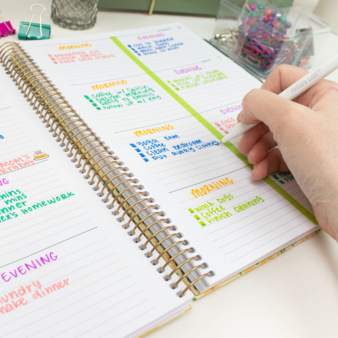 Person writing in a spiral-bound planner with colorful tasks