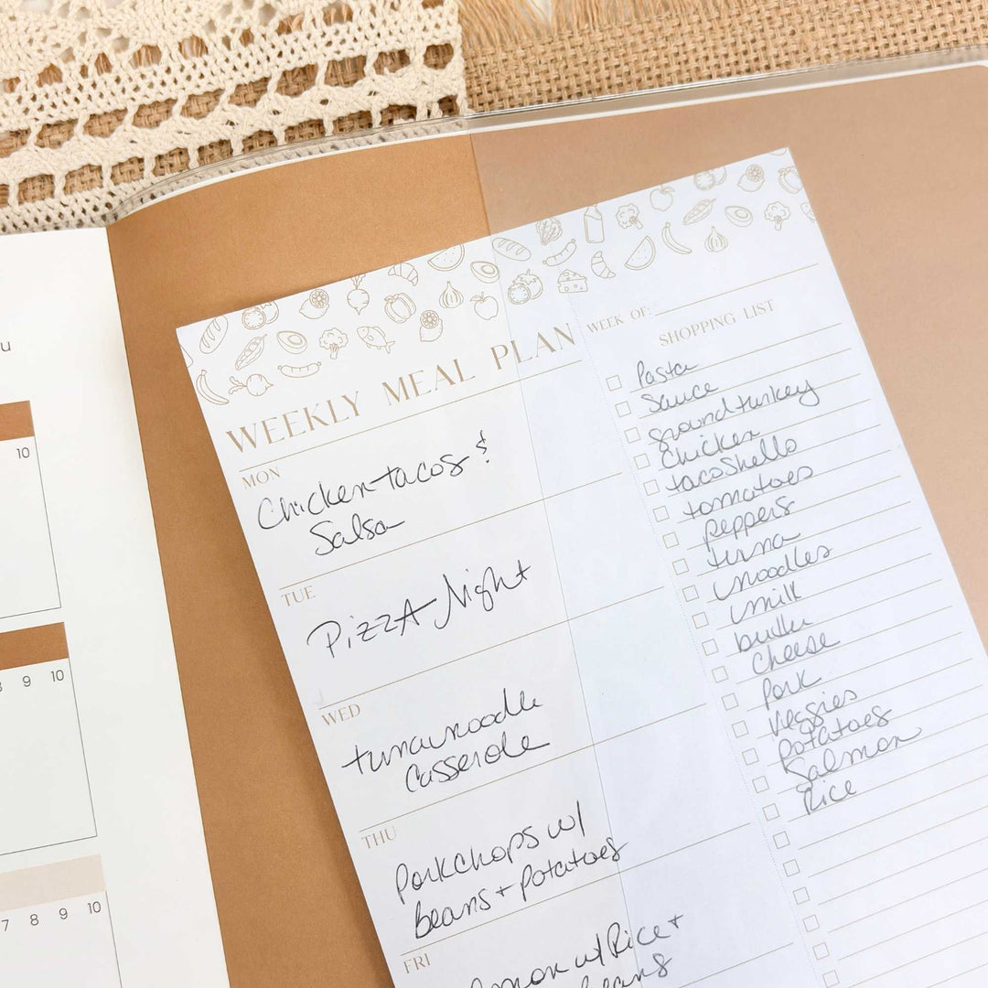 Weekly meal plan sheet with food items and checkboxes on a beige surface.