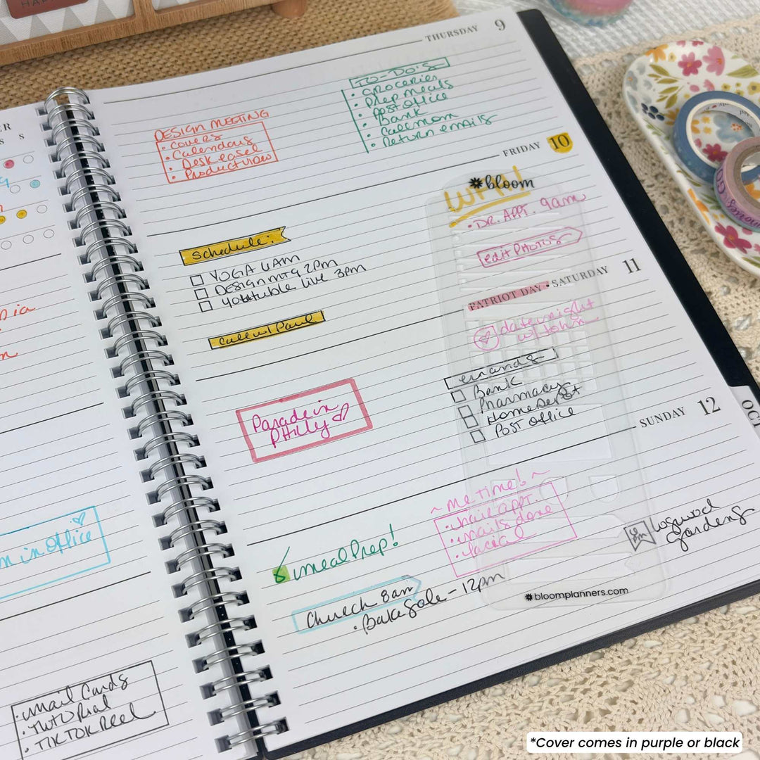 An open spiral-bound planner or journal showing weekly lined pages with handwritten notes and colorful printed headers in red, green, blue, yellow, and purple. A small text note in the bottom right says the cover comes in purple or black.