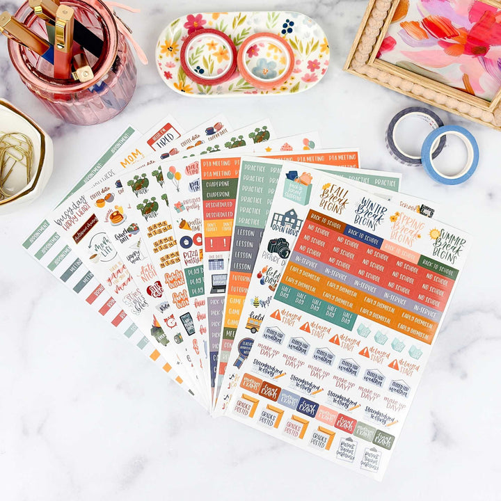 Set of colorful mom of school ages kid themed planner stickers on a white surface with stationery items.