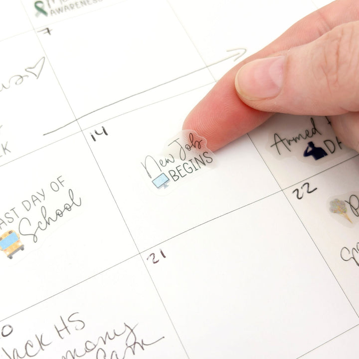 Hand pressing holiday date sticker onto planner page