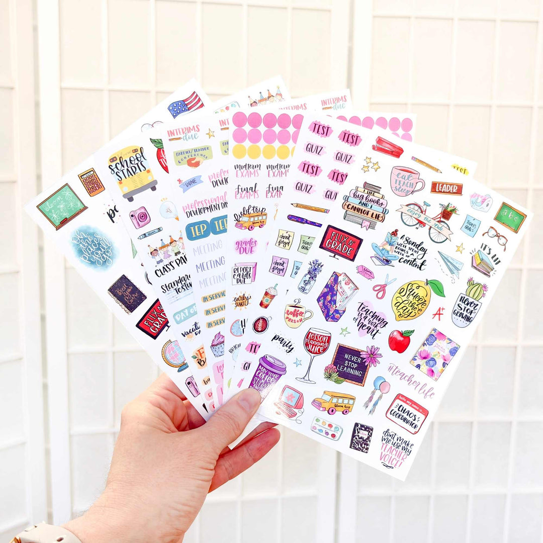 Hand holding a sheet of colorful planner stickers against a light background
