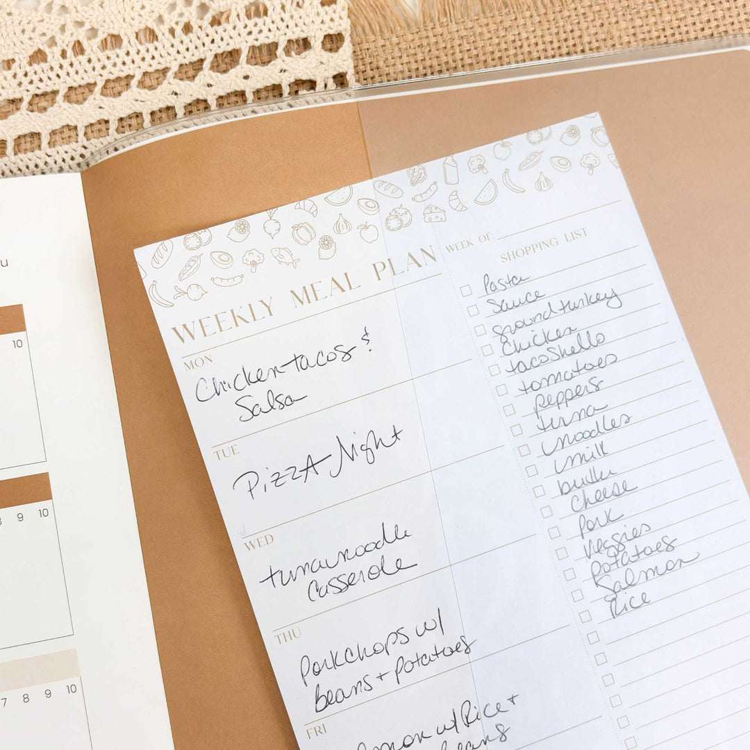 Weekly meal plan sheet with food items and checkboxes on a beige surface.