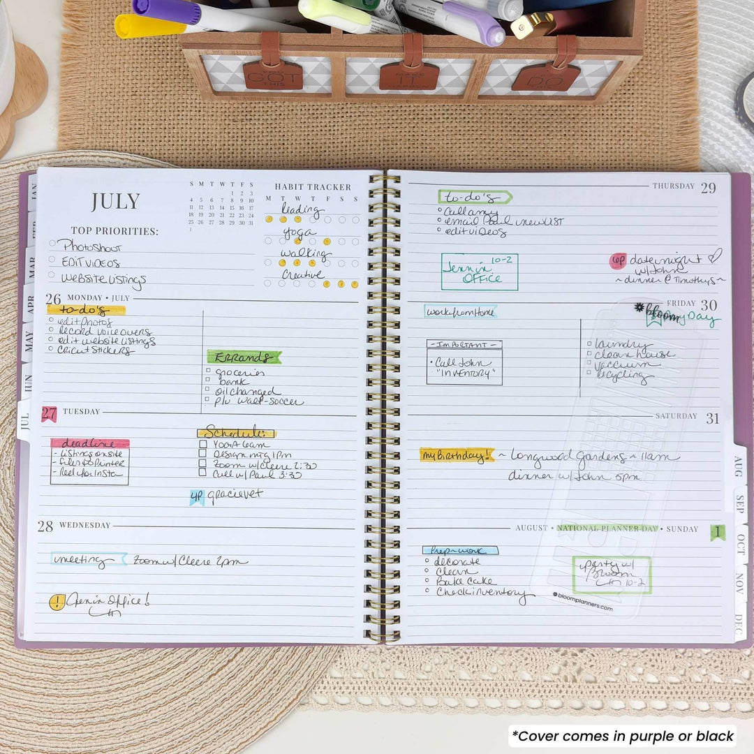 An open spiral-bound planner showing a weekly layout for July, with handwritten notes and colored highlights. The cover is partially visible as purple and black.