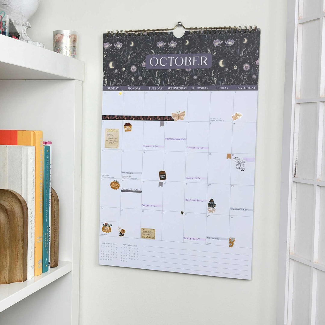 Wall calendar for October on a white wall with books below