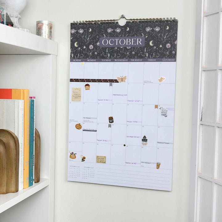 Wall calendar for October on a white wall with books below