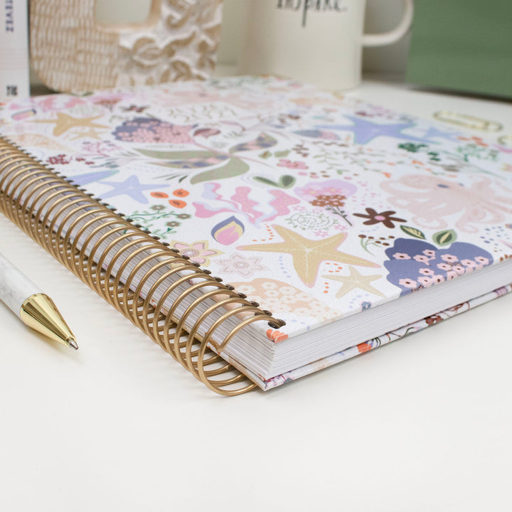 Floral planner with a pen on a white surface