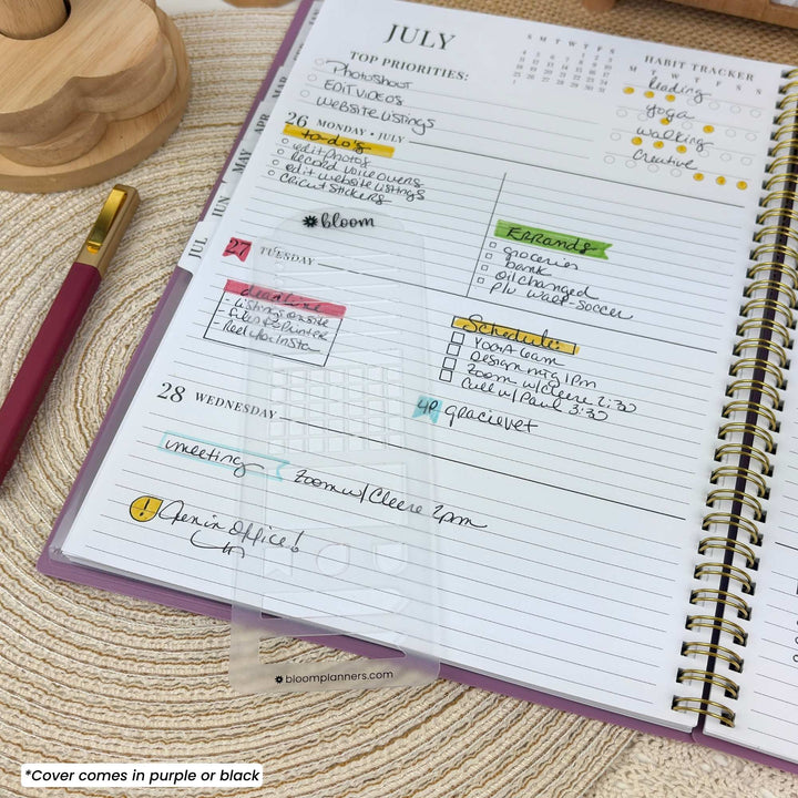 A clear plastic cover with a printed weekly planner layout is shown resting over an open purple spiral notebook. The cover features sections for top priorities, weekly summaries, a weekday tracker, and a schedule, with some handwritten text visible underneath.