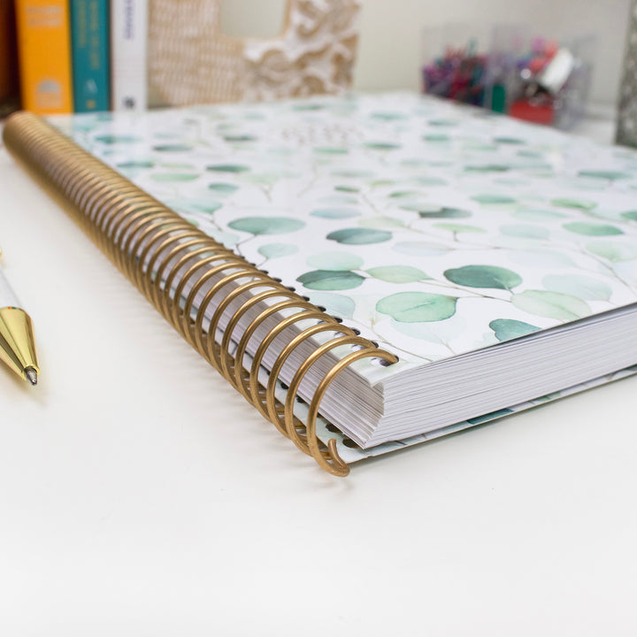 Side view of a planner with gold metal binding. 
