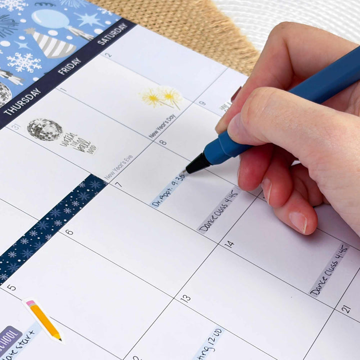 Hand with a pen marking a date on a calendar