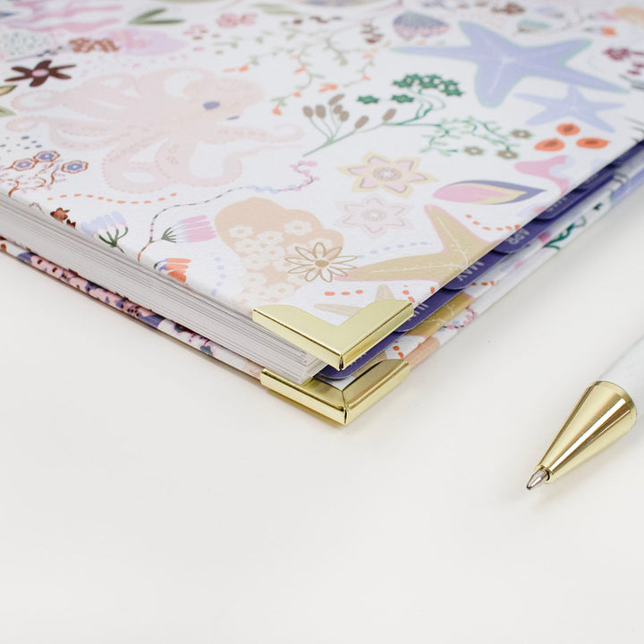 Floral planner with a gold pen on a white surface