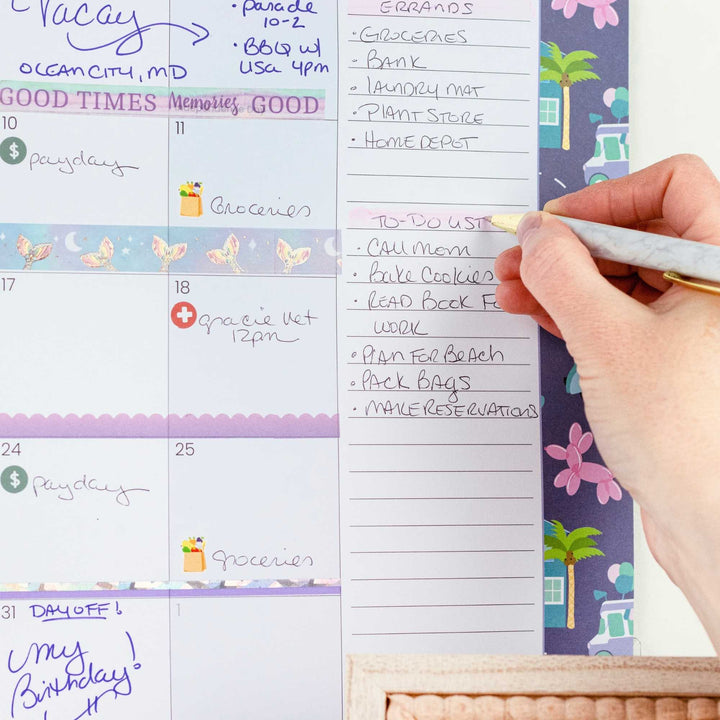 Hand holding a pen over a planner with notes and to-do lists.