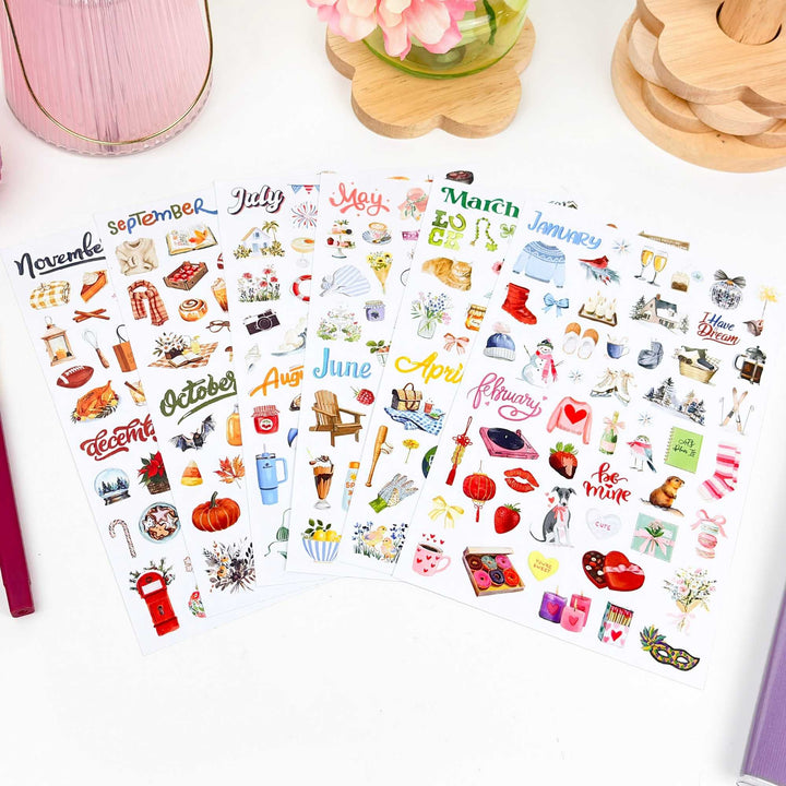 All six sheets fanned out on a white desk with pink flowers in background