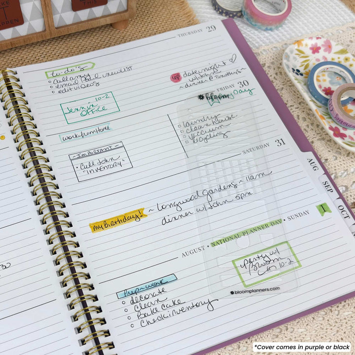An open spiral-bound planner showing a weekly layout with lined pages, handwritten notes, and decorative washi tape rolls on a woven surface.