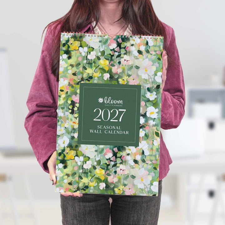 Person holding a 2027 floral wall calendar