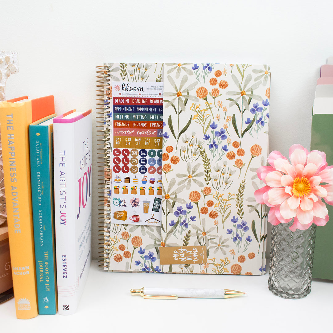 Planner with floral design, highlighting a back cover pocket with free stickers and a magnetic bookmark.