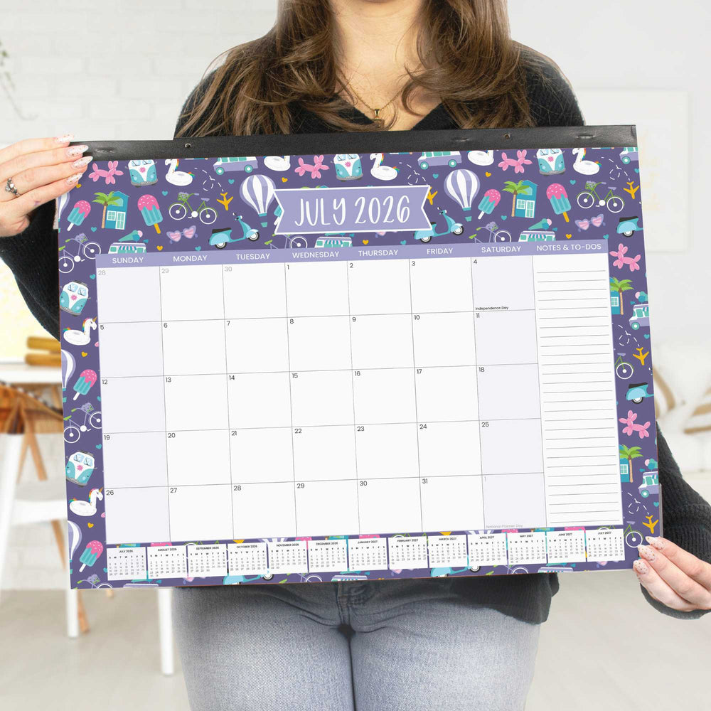 Person holding a large colorful calendar for July 2026 with various designs on a white background.