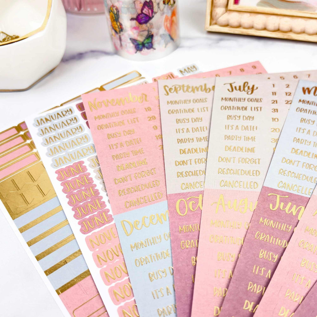 Set of planner stickers with months and motivational phrases on a white surface.