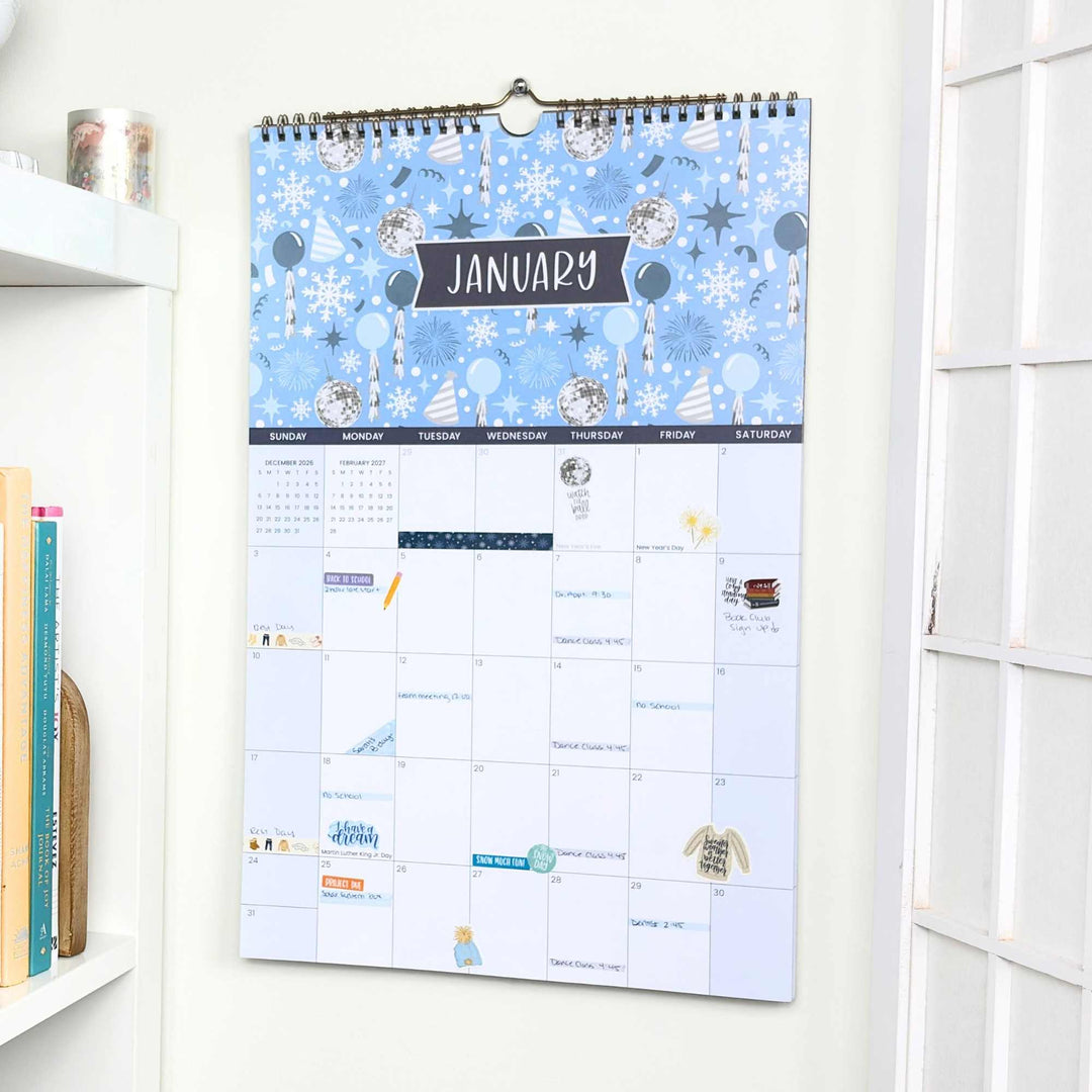 Wall calendar with a blue winter-themed cover on a white wall