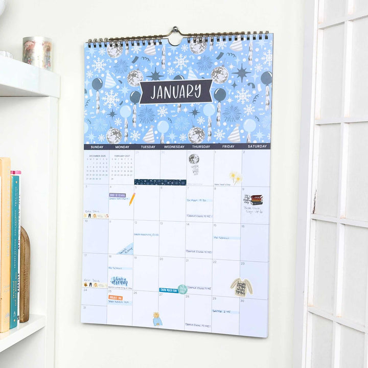 Wall calendar with a blue winter-themed cover on a white wall