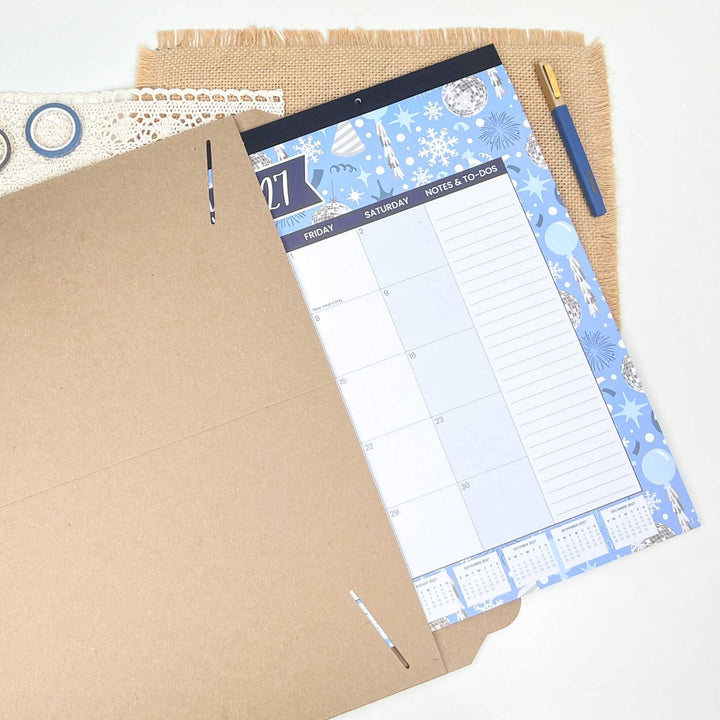 Planner with blue and white design on a textured surface with a pen.