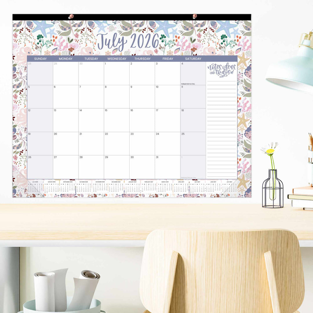 Floral-themed wall calendar for July 2026 on a desk