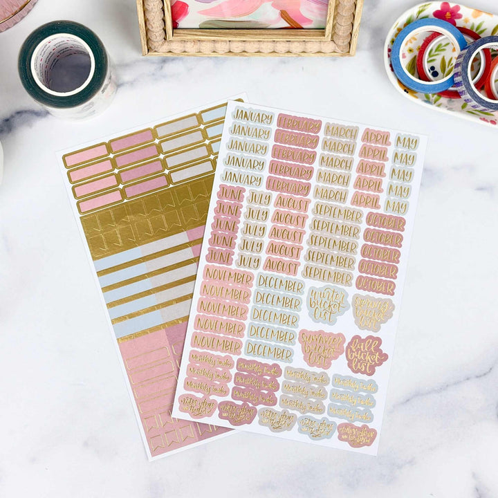 Sticker sheets with months and gold designs on a marble surface