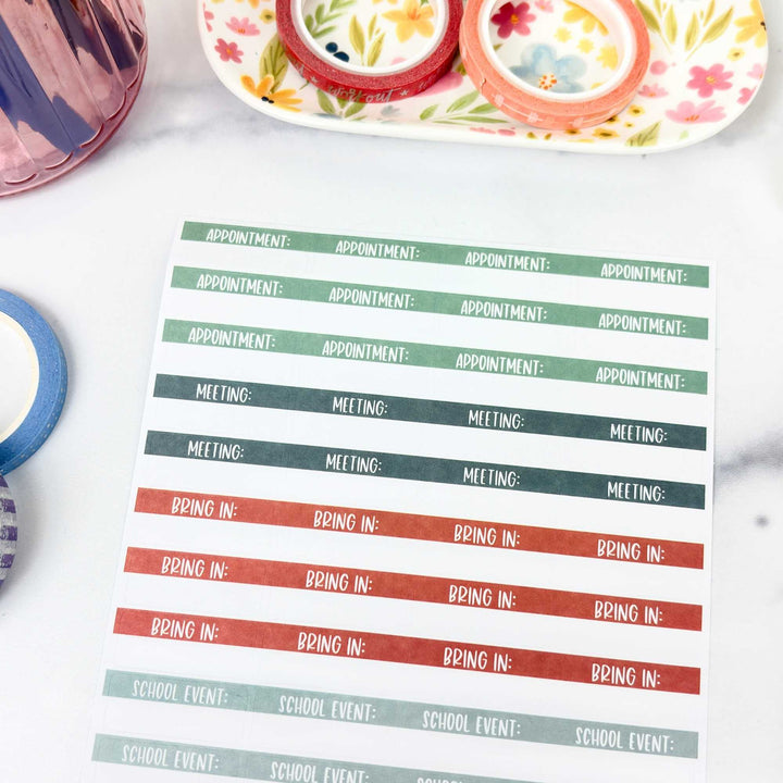 Sheet of colorful planner stickers with text on a white surface.