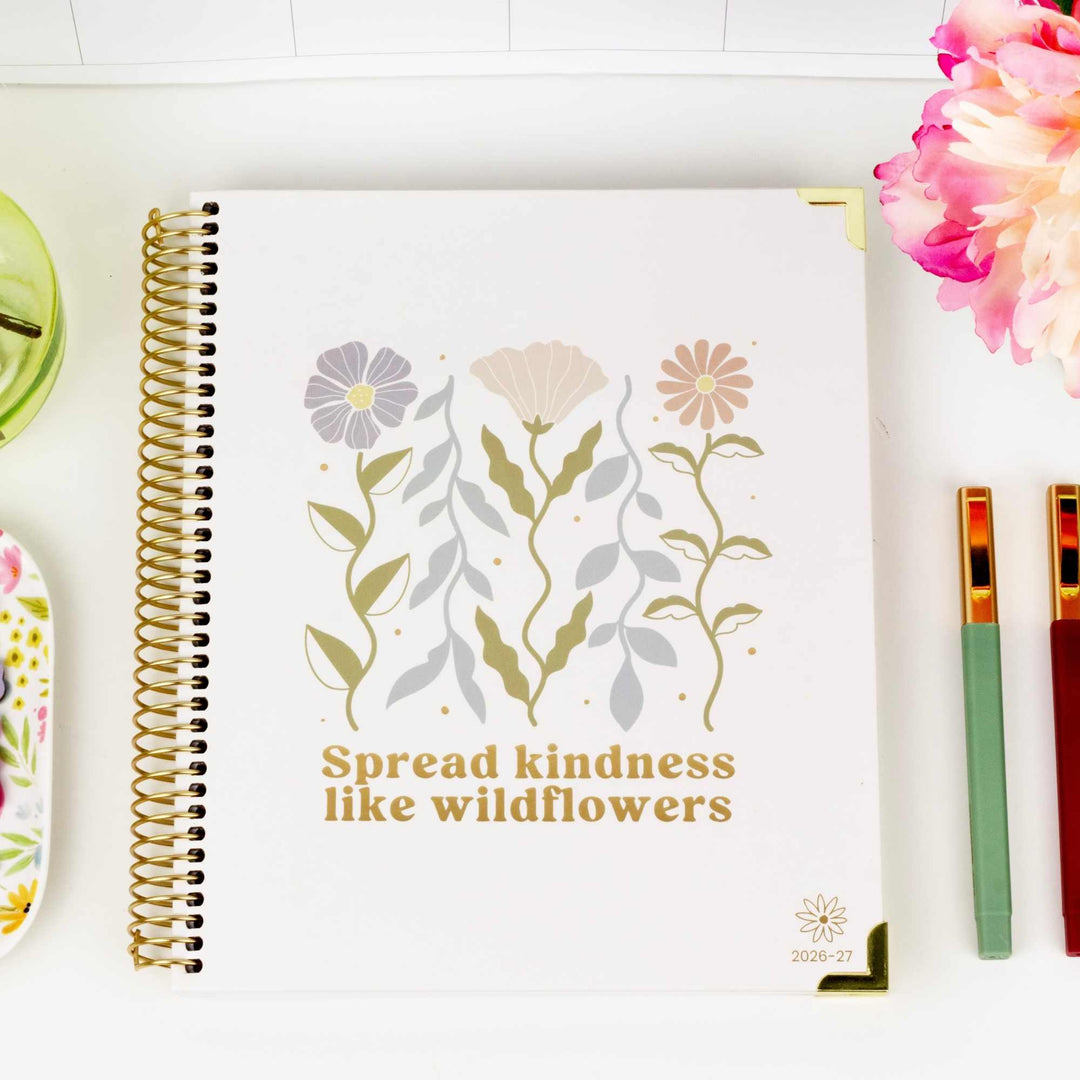 Vision planner on desk with soft and pretty retro floral design. Neutral colors with beige background on the cover. 