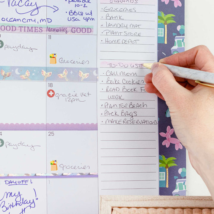 Hand writing on a planner with a colorful design on the right side